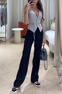 Détail d'un gilet gris à col en V avec un pantalon noir à taille haute et jambe large