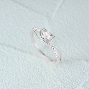 Macro detail of silver heart ring featuring sparkling cubic zirconia and twisted band