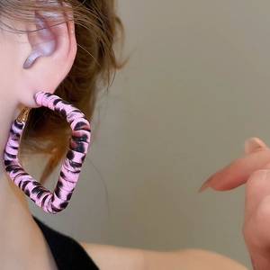 Gros plan d'un mannequin portant de grandes boucles d'oreilles carrées imprimé léopard rose