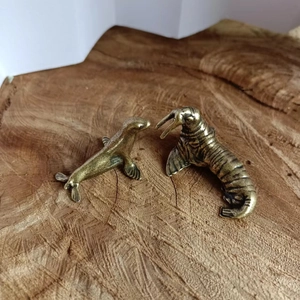 Detail of vintage solid copper walrus and sea lion miniatures on natural wood