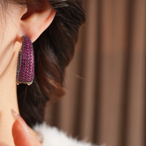 Close-up of vintage C-shaped earrings with purple zircons on a high-end metal base