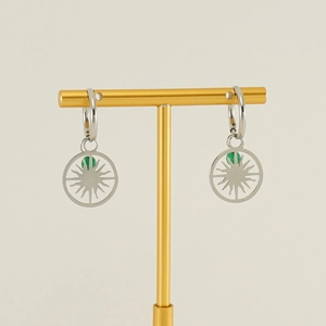 Macro detail of silver hollow sun pendant earrings with a green bead on a T-bar stand