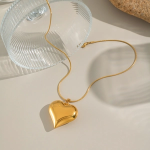 Dettaglio della collana a cuore in oro 18K con catena a serpente su vetro