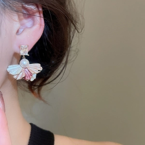 Close-up of fan-shaped pearl earrings with gold plating and pink gradient petals
