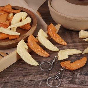 Realistic mini chicken wing tip pendant keychain on a wooden table display