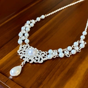 Détail du collier baroque argenté avec perles et strass sur surface en bois brun