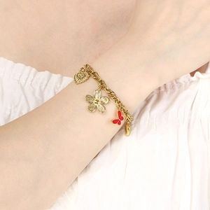 Detail of 18K gold-plated stainless steel bracelet with heart and floral charms on a wrist