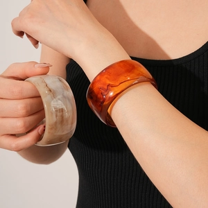 Close-up of chunky vintage resin bangles in amber orange and marble white textures