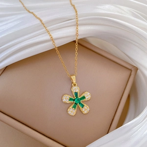 Detailed close-up of a gold flower pendant necklace with green and clear zircon stones