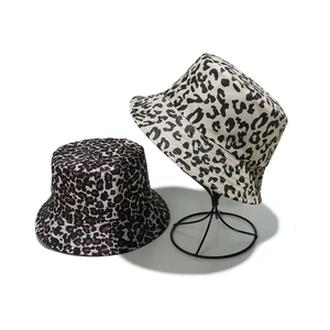 Two stylish leopard print bucket hats in brown and white canvas on a display stand