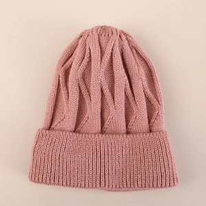 Detalle del tejido de punto de un gorro rosa cálido con diseño de ondas y borde acanalado