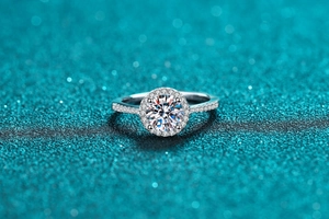 Macro shot of silver Moissanite ring with halo setting and pavé diamonds on blue glitter