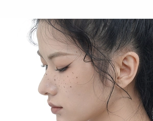 Macro detail of natural light brown faux freckle patches on nose and cheeks of a model