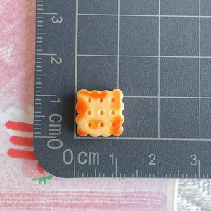Macro shot of 1cm resin bread biscuit miniature on a ruler for size reference