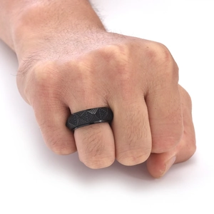 Nahaufnahme eines schwarzen Edelstahlrings mit geometrischer Prägung an einer Männerhand