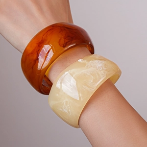 Macro shot of wide resin bangles in amber tortoiseshell and creamy marble patterns
