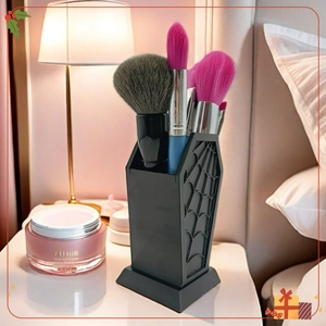 Gothic coffin-shaped makeup brush holder with spiderweb relief on a cozy vanity table