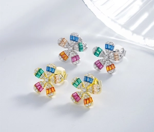 Macro shot of silver and gold flower stud earrings with colorful zircon gemstones