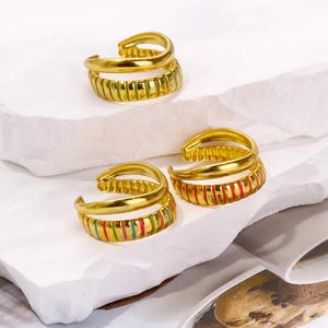 Three-piece gold plated open rings with colorful enamel stripes on a stone display