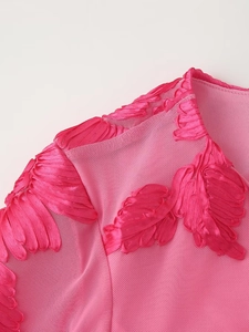 Détail du tissu en maille rose avec broderie de plumes brillantes sur la robe