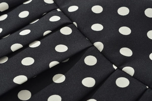 Vue macro détaillée du tissu noir à pois blancs avec une texture plissée élégante