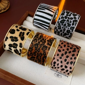 Macro shot of five animal print cuff bracelets with gold plating on a jewelry tray