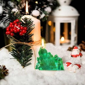 Bougie en cristal vert avec décor de baies de pin dans un décor de Noël enneigé