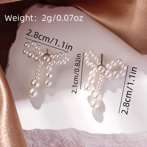 Detail view of bow-shaped pearl earrings with gold finish and specific size measurements