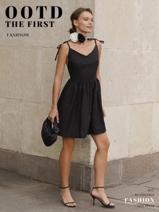 Scatto street style di un mini abito nero in cotone senza schienale con spalline sottili e accessori
