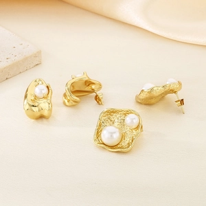 Détails de boucles d'oreilles en acier doré 18k avec perles sur fond de tissu beige