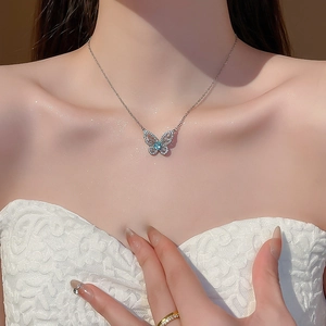 Detail of zircon butterfly pendant with blue gemstone worn on a model's collarbone
