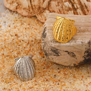 Shell shaped rings in gold and silver finish placed on a beach sand and rock background