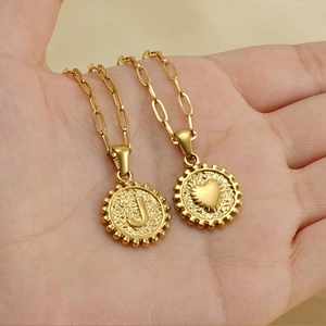Detail of 18K gold paperclip chain necklace with round letter J and heart pendants