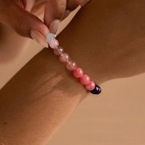 Macro detail of natural pink crystal beaded bracelet with floral energy and birthstone card