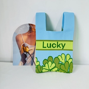 Sky blue knitted tote bag featuring a green clover pattern and Lucky text design