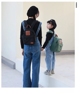 Matching black adult and green kids canvas backpacks with smiley face leather patches