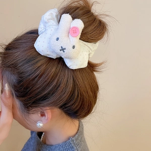 Close-up of white plush bunny hair tie with pink polka dots on a stylish bun hairstyle