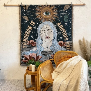 Bohemian woven tapestry with sun, moon, and tassels hanging in a cozy indoor setting
