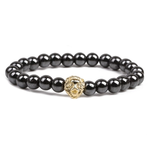 Detailed shot of hematite beaded bracelet featuring a golden lion head charm on white background