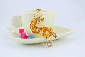 Detailed view of a golden dragon keychain with crystal texture and an ancient coin charm