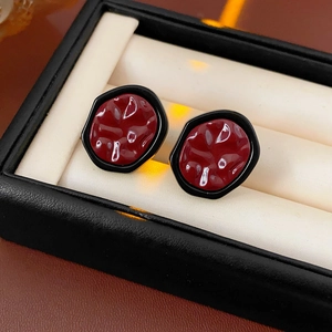 Macro shot of retro geometric earrings with dark red finish and black metallic frame