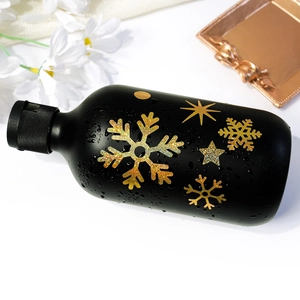 Detailed view of gold and iridescent snowflake stickers applied to a black matte cylinder
