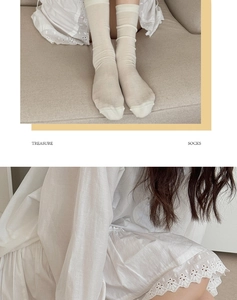 Close-up of cream white silk knit socks styled with elegant embroidery dress
