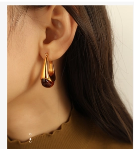 Close-up of vintage gold teardrop earrings with amber resin pendant worn by a model