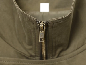 Macro view of olive green cotton fabric with high-quality bronze metal zipper detail