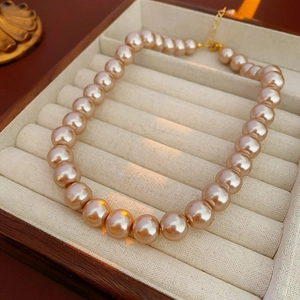 Macro detail of elegant champagne pearls with gold clasp in a beige velvet jewelry tray