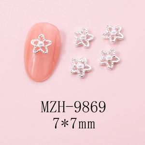 Macro view of star-shaped nail charms with white pearls on a pink background