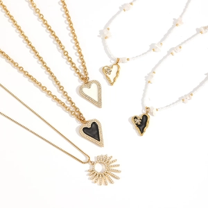 Set of gold heart pendant necklaces with pearls and zircons on a white background