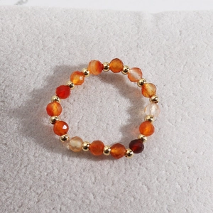 Detailed macro of orange faceted beads and gold metal spacers on an elastic ring