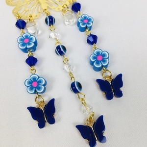 Detailed macro view of gold butterfly and blue flower charms for car hanging ornament